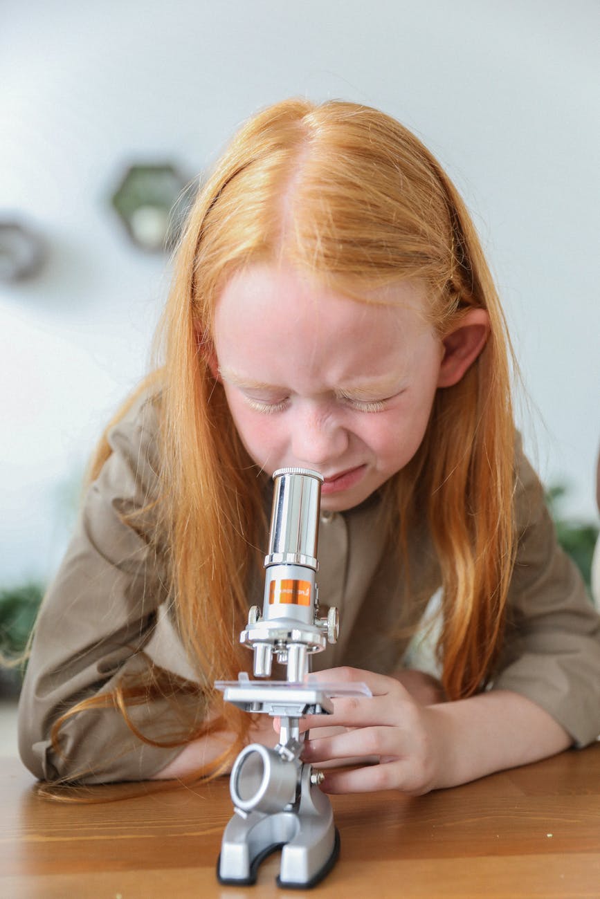 concentrated kid using microscope in science class